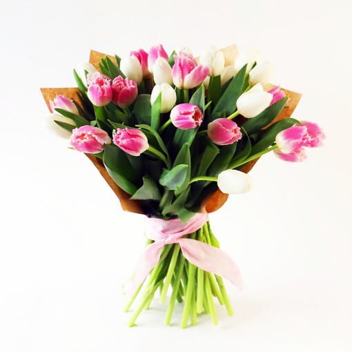 Ramo de tulipanes blanco y rosados envuelato en papel decorativo.